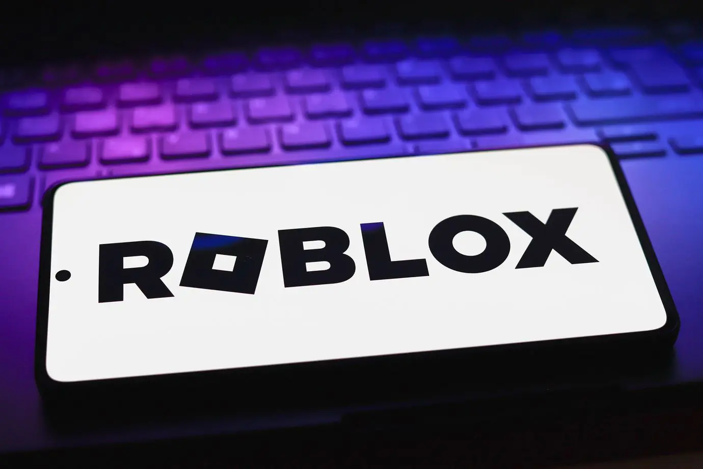 Roblox logo on a smartphone with a gaming keyboard